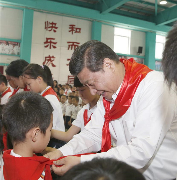 2014年5月30日,在北京市海淀区民族小学的少先队入队仪式上,习近平为新少先队员系上红领巾。